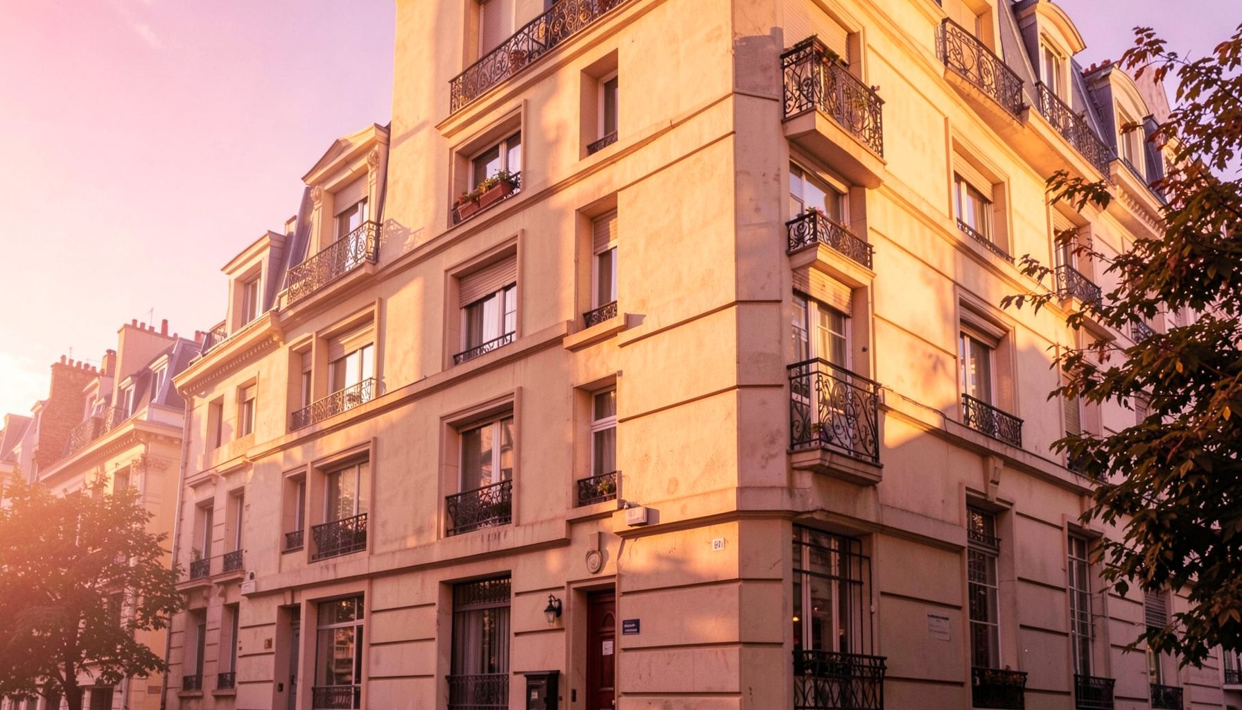 Façade contemporaine d'un immeuble résidentiel parisien baigné de lumière dorée de fin d'après-midi, tons crème et pierre, ambiance chaleureuse et accueillante